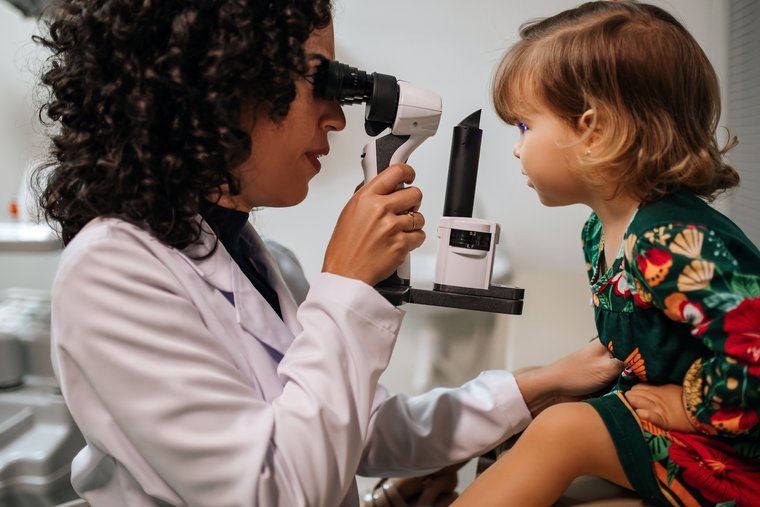 Dra. Thaís Nunes examinando os olhos de uma criança pequena